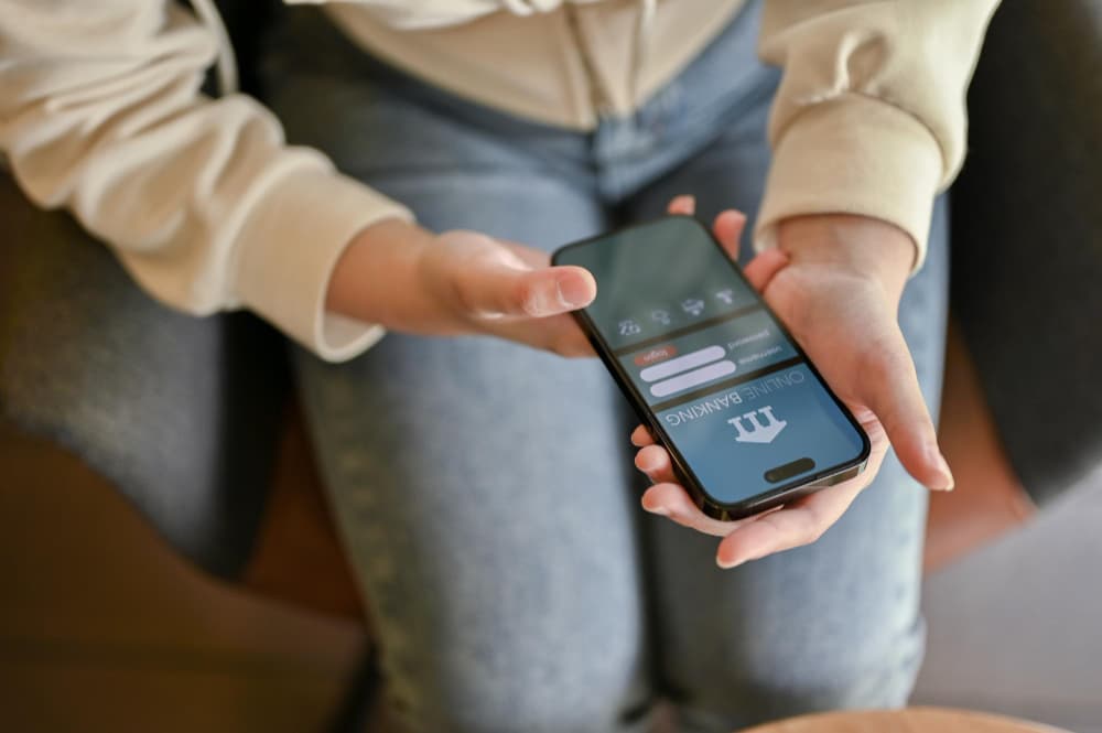 Person holding a phone open to a mobile banking login screen