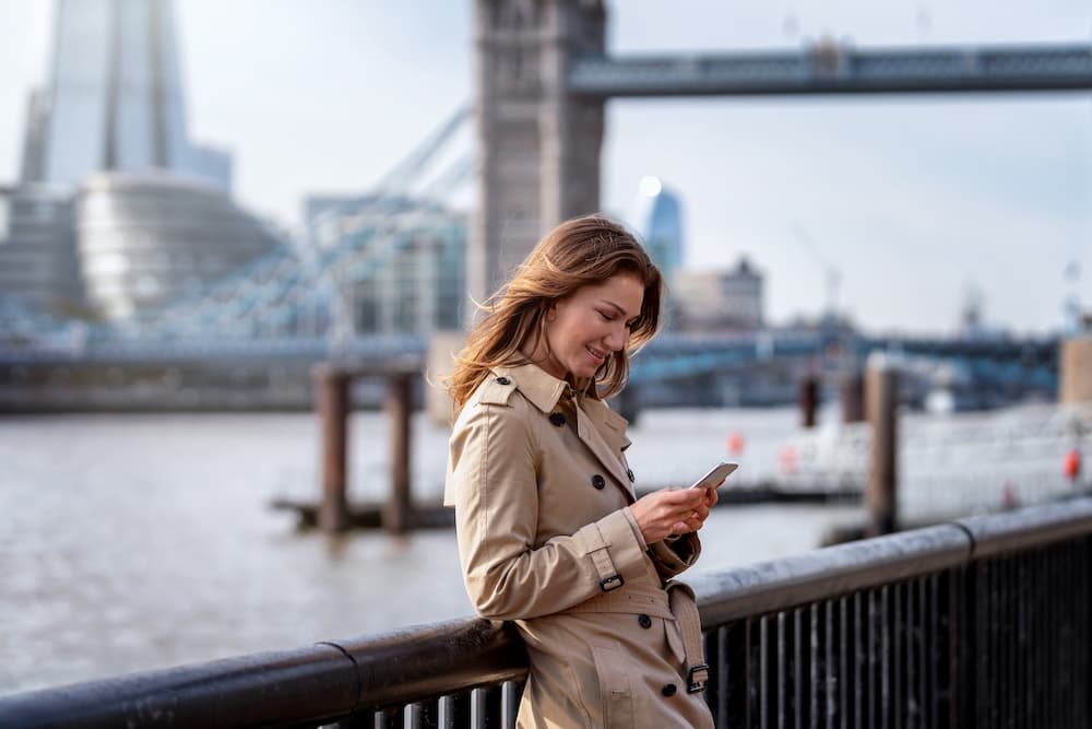 Woman using her phone near Tower Bridge in London