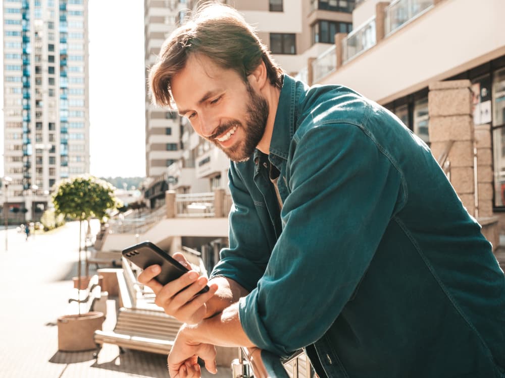 Man standing in the sun while enjoying mobile internet from Firsty