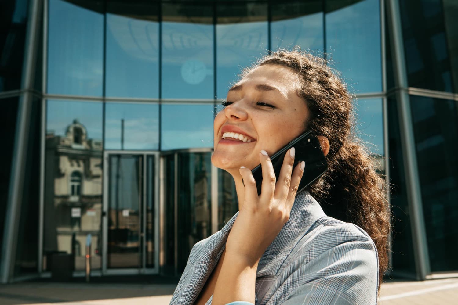 Woman smiling while making a phone call outside an office building