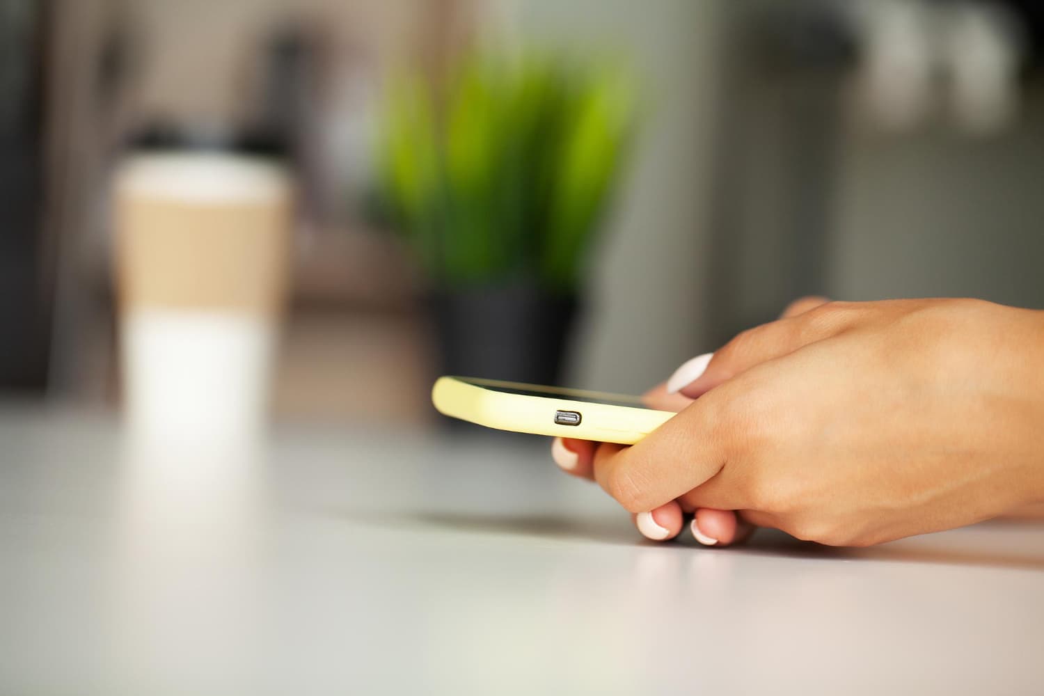 Hand holding a phone at a cafe table