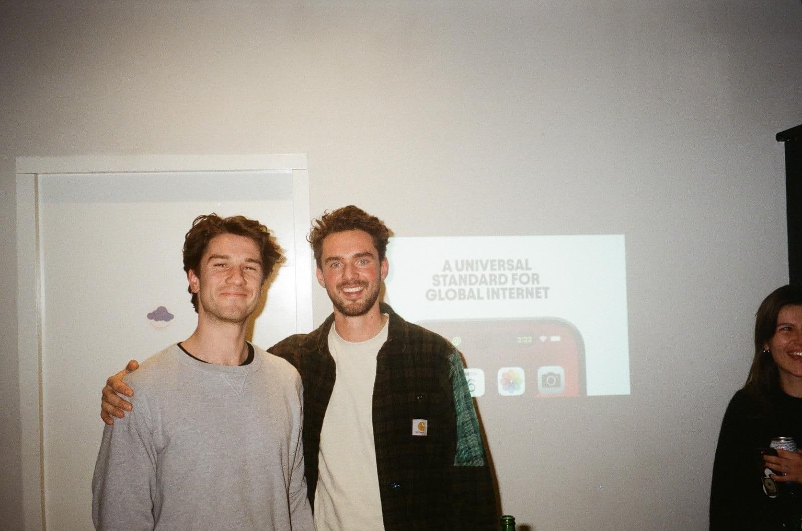 Firsty's co-founders at a company event with a slide on global internet standards