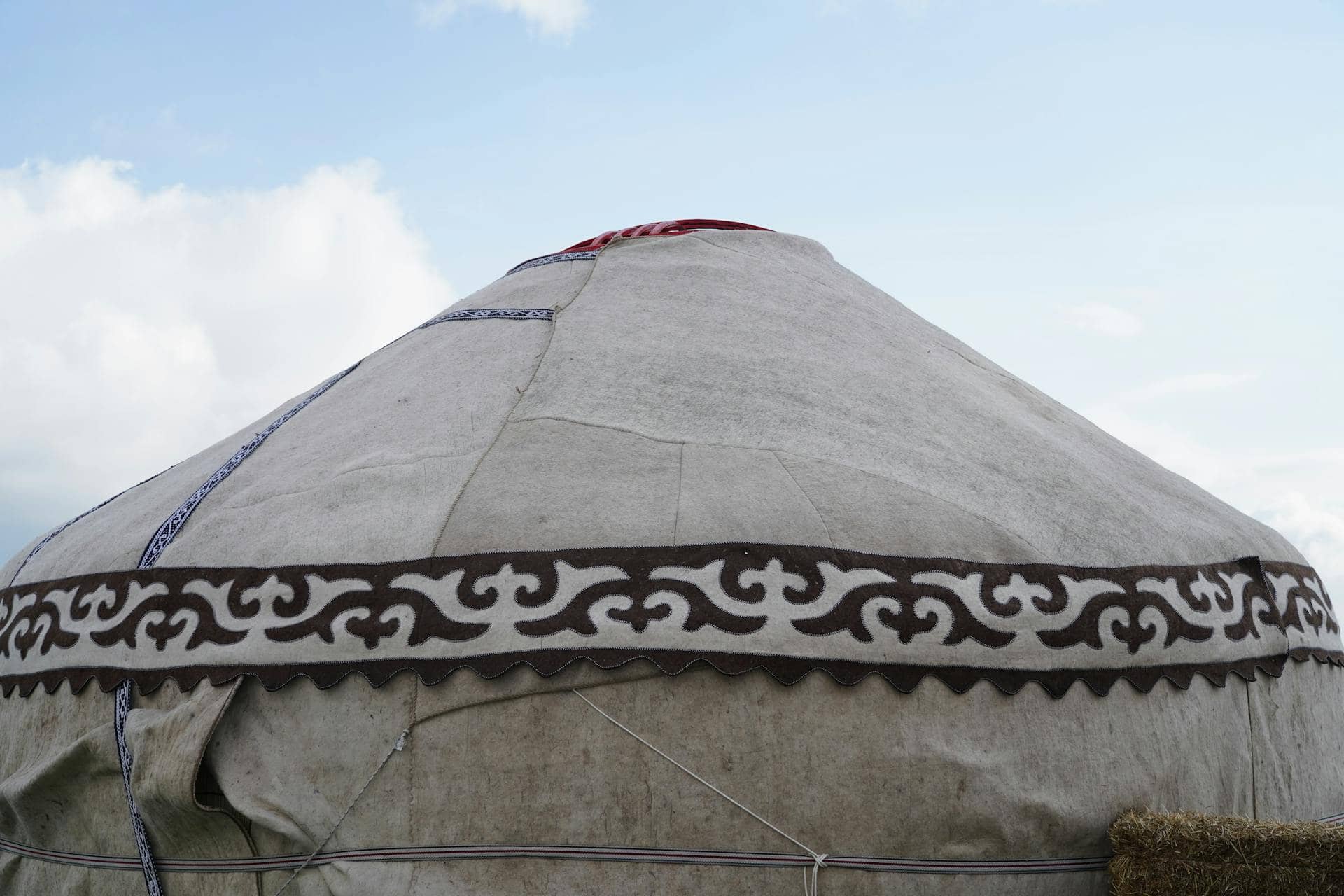 Traditional yurt tent with decorative patterns under a blue sky.