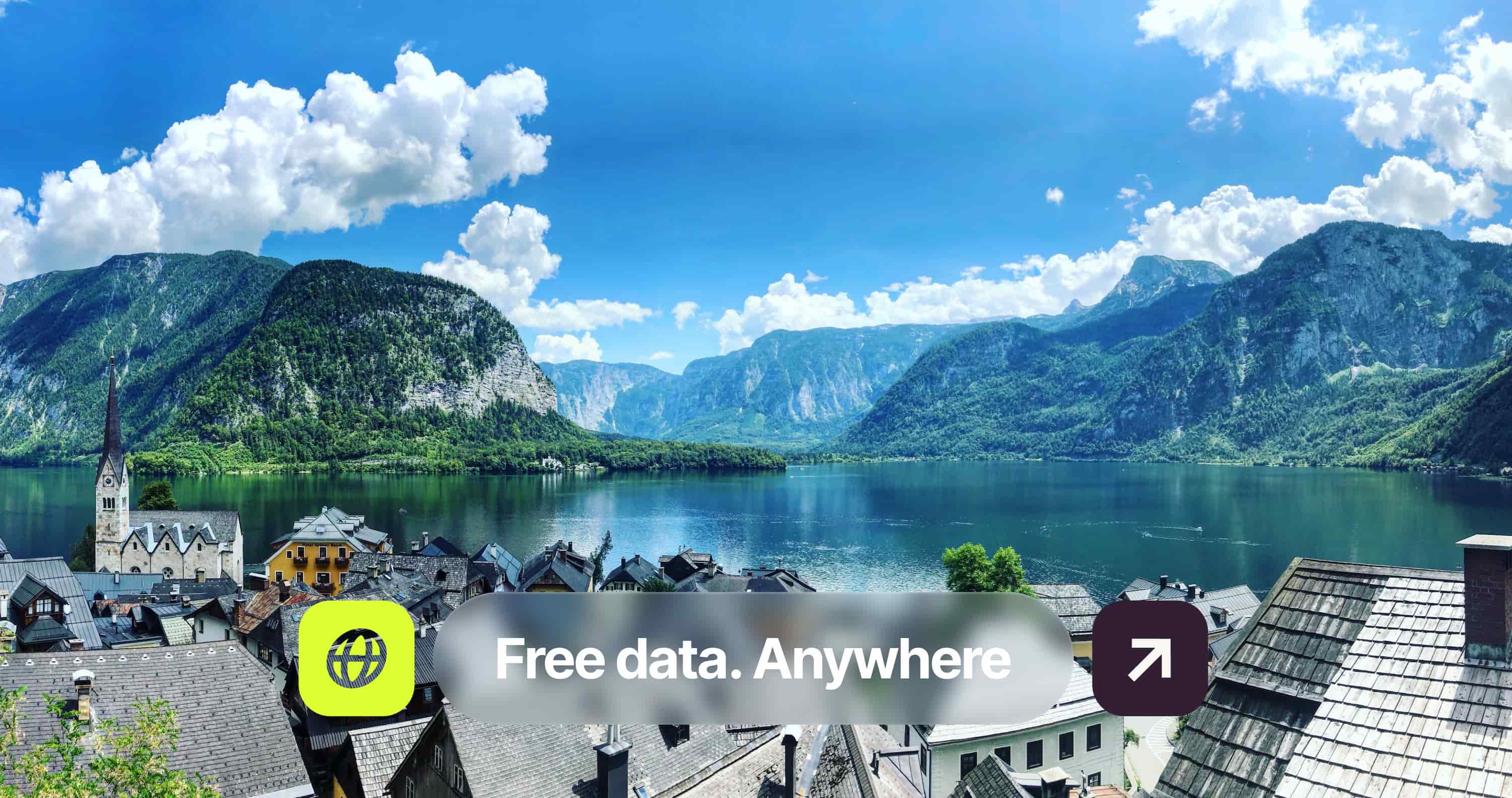 Scenic view of a lake surrounded by mountains and a quaint village with a church, under a blue sky with fluffy clouds. Text overlay: "Free data. Anywhere".