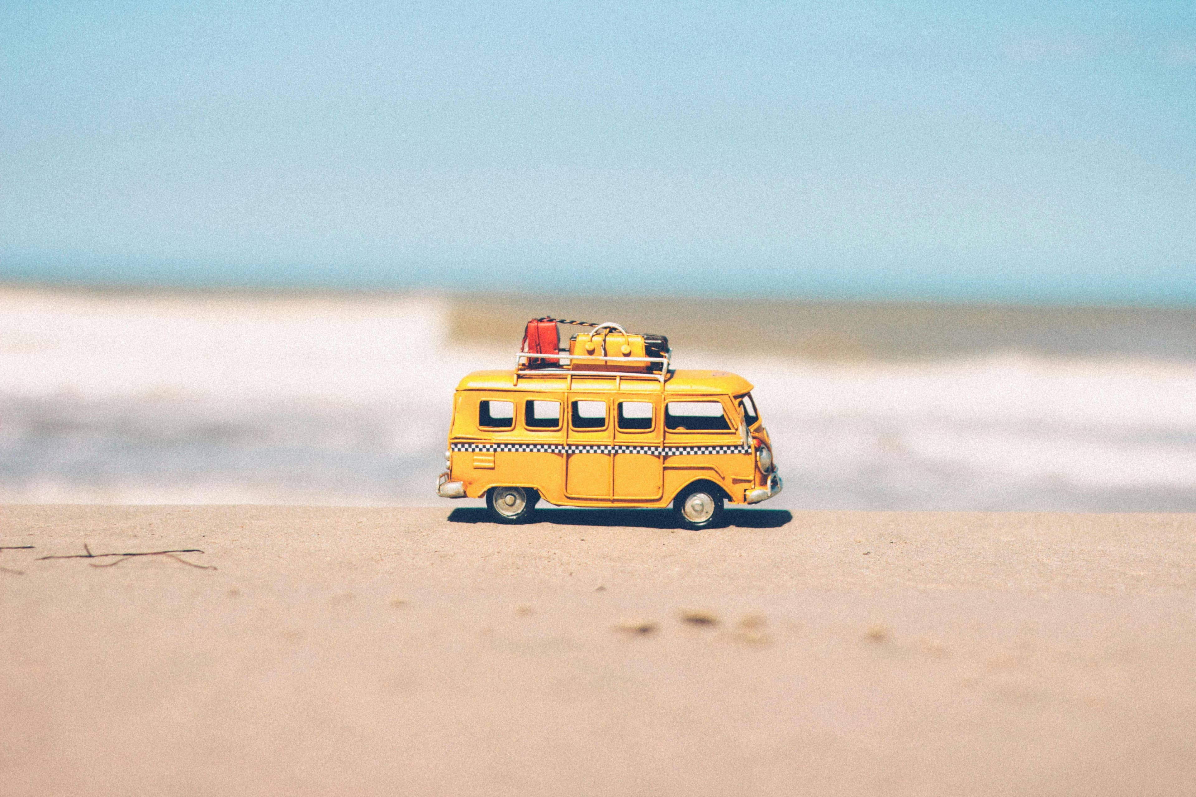 Toy camper van with luggage parked on a sandy beach
