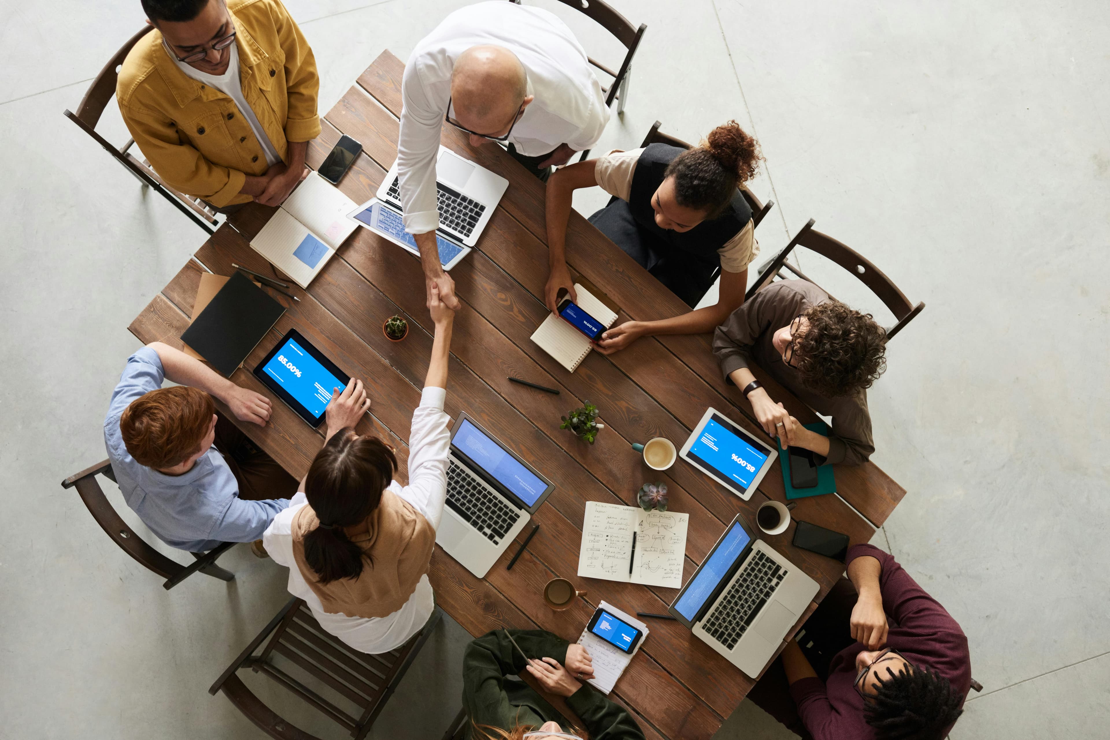 Overhead view of a team collaborating around a table with laptops