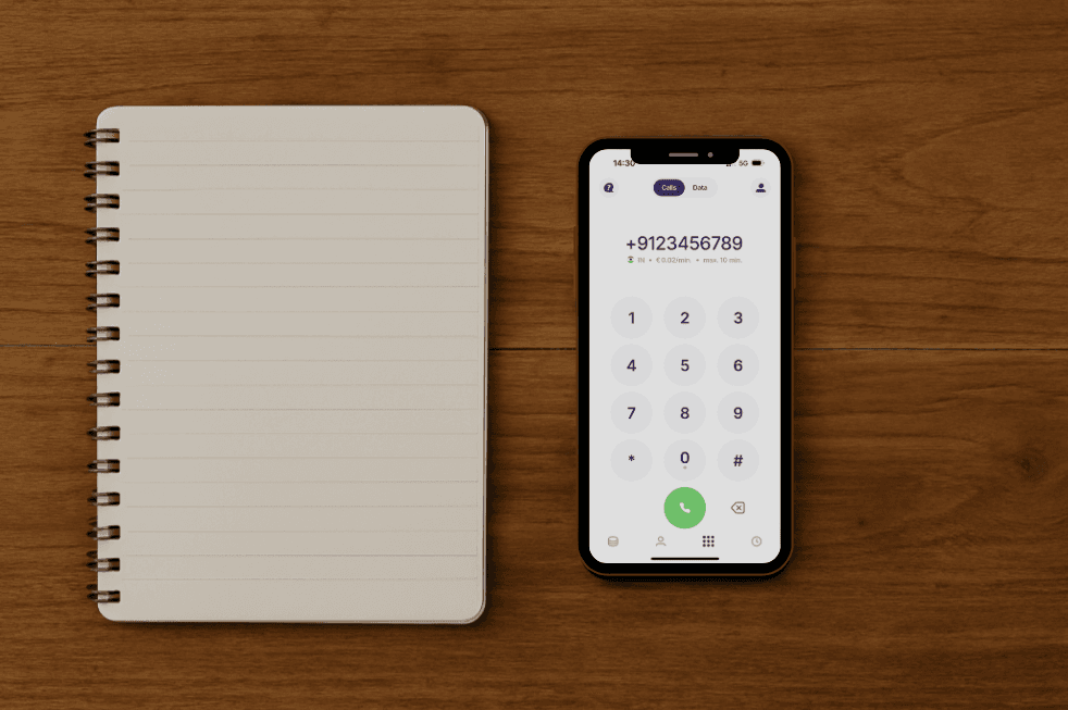 Open notebook and smartphone with dial screen on a wooden surface, showing cheap  calling to india