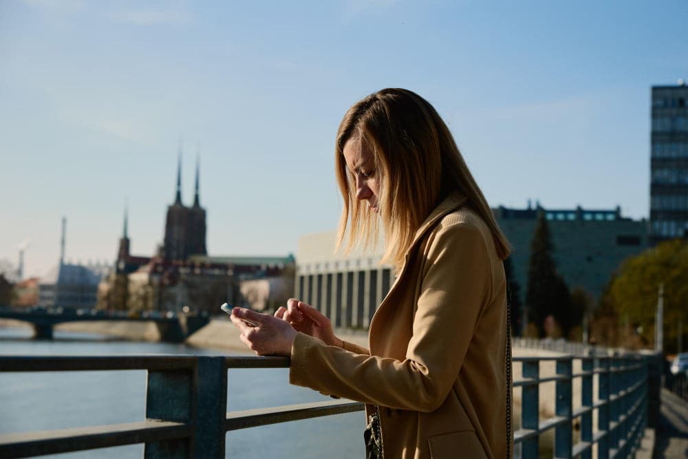 Traveller checking her phone on a bridge in a German city