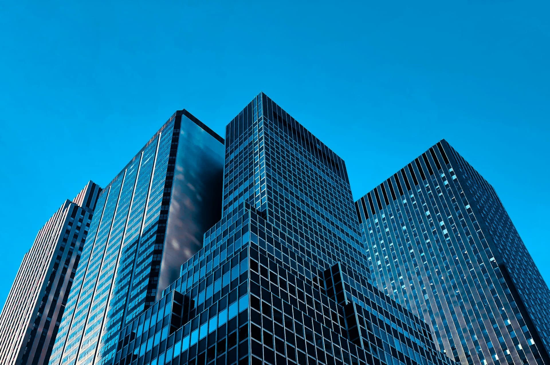 Glass office towers viewed from below against a blue sky