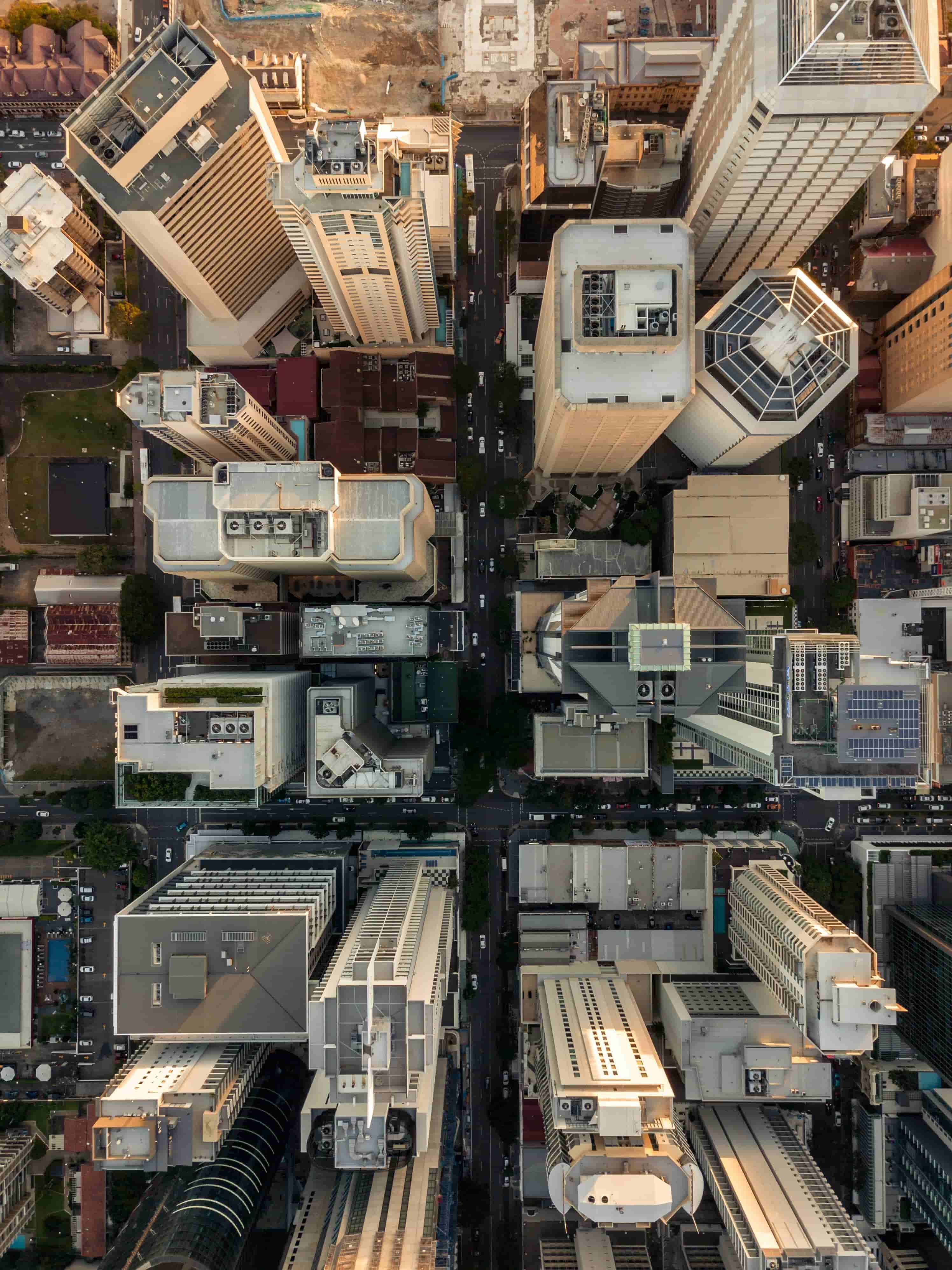 Aerial view of a cityscape with tall buildings, streets, and intersections, showcasing urban architecture from above in warm lighting.