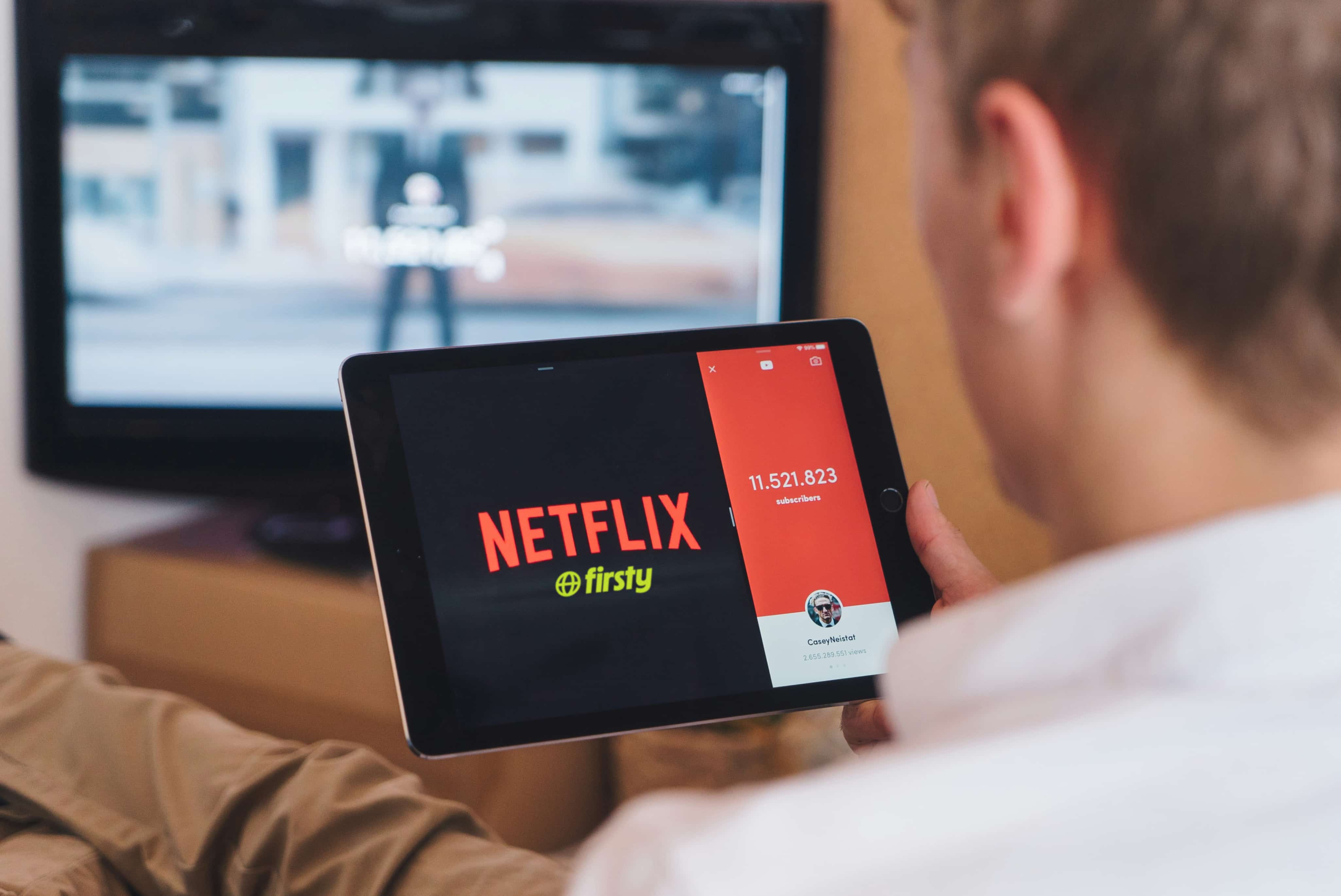 Man watching Netflix on a tablet with Firsty eSIM, streaming Netflix in 185+ countries without roaming charges.