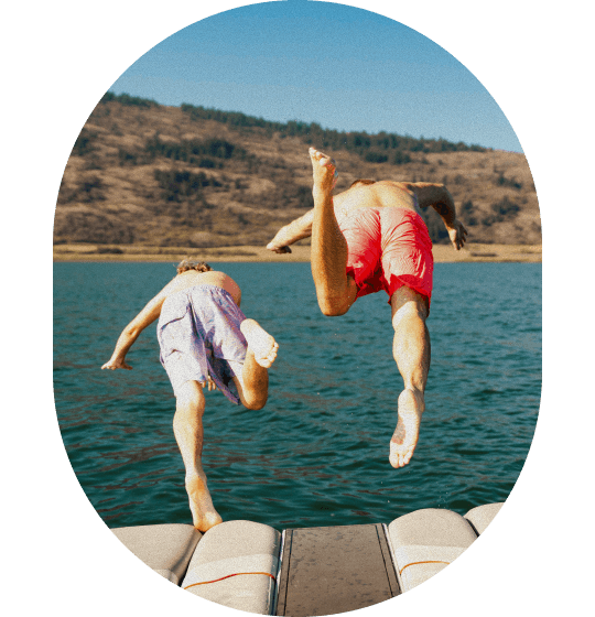 Two friends leaping off a boat into a lake together